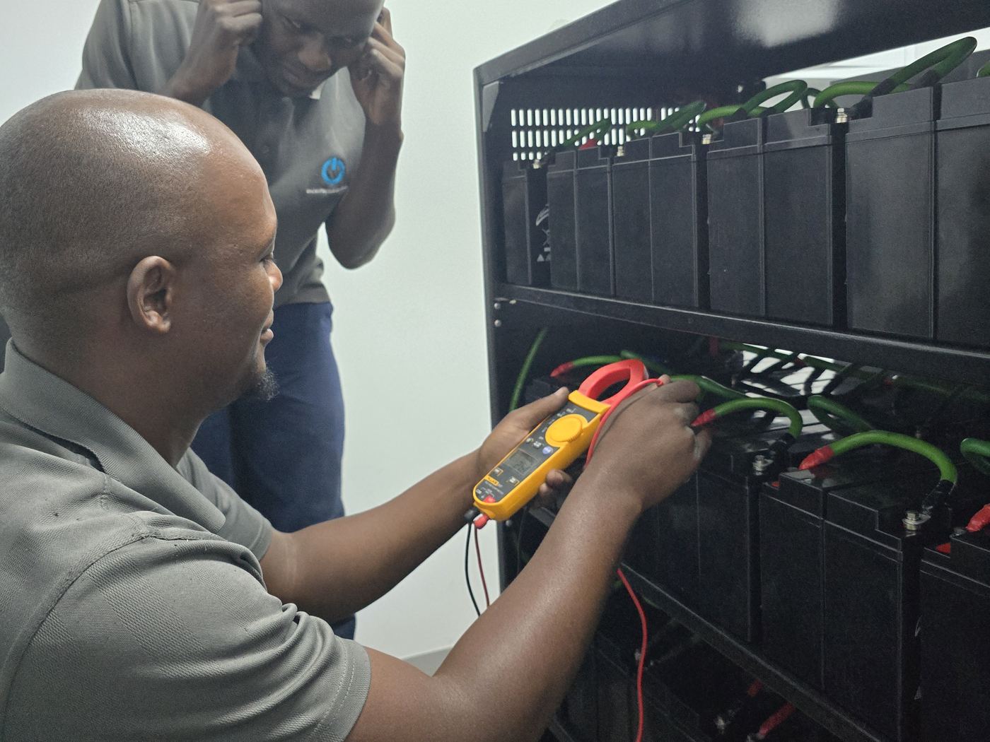 Technician testing battery strings with a clamp meter